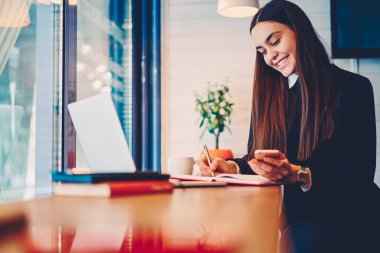 Genç öğrenci bilgi rapor yapıyor Smartphone'da göz Web sitesinden belirterek gülümseyen.