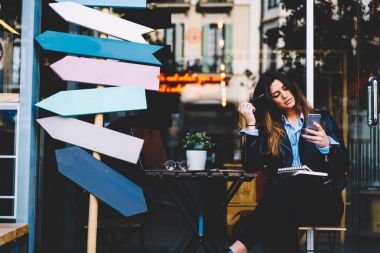 Serbest zaman açık havada açılan dizüstü bilgisayar aygıtla kafede oturan modern cep internet sitelerinde tarama çekici öğrenci.