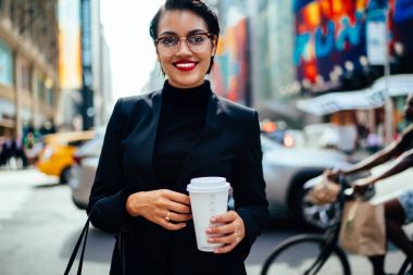 Başarılı kadın girişimci kahve go ile kentsel arka plan üzerinde dururken kamera seyir varoluş portresi.