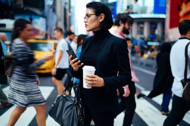 Formal giyim uzak uygulama kahve ile sokak üzerinde telefon duran çevrimiçi haritalar ile gitmek için kullanırken seyir dalgın kadın Yöneticisi.