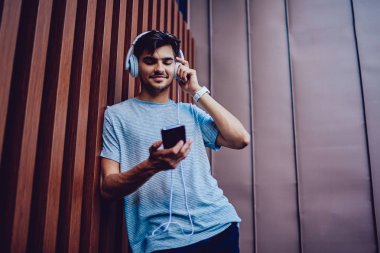Smartphone üzerinden müzik dinlerken neşeli adam portresi.