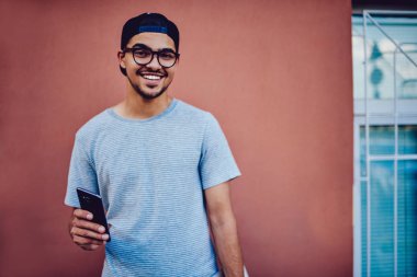 Son moda gözlük telefon kullanarak neşeli hipster adam portresi.