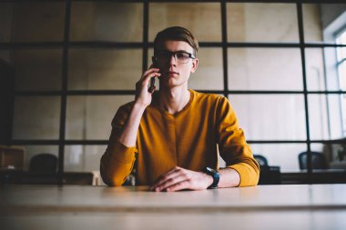 Ciddi gurur CEO'su alan masada coworking oturan telefon konuşmayı portresi.