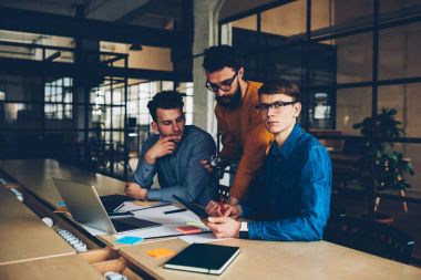 Dizüstü bilgisayar kullanırken ofiste proje işbirliği için görüntüleri düzenleme üzerinde çalışan fotoğrafçılar profesyonel grup