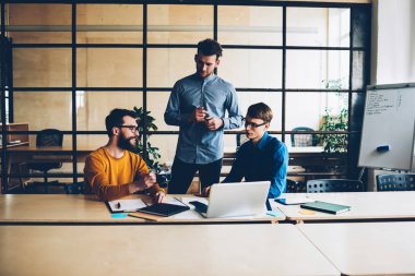 Erkek mürettebatı bu toplantı sırasında tasarımcıların oturum tartışırken fikirler ve çözümler birlikte beyin fırtınası sahip profesyonel takım genç Ceo programları modern dizüstü bilgisayarda sunmak geliştiriciler