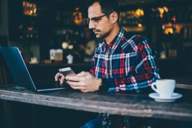 Öyle şık gömlek çalışma serbest dijital dizüstü bilgisayarda başarılı program oluşturma geliştirici yan. Erkek gözlük netbook üzerinde video izlerken telefon elinde tutan