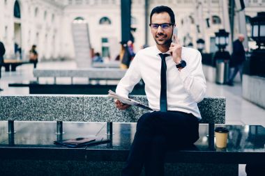 Mobil istemcilerle modern cihaz kullanarak iyi bir atmosfer içinde konuşmayı iyi görünümlü başarılı icra müdürü. Profesyonel avukat açık havada gadget ve gazete ile vakit gülümseyen