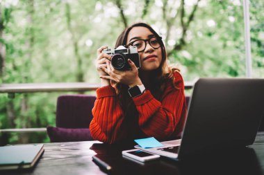 Dizüstü bilgisayar, eski vintage fotoğraf makinesinde fotoğrafların hobi vakit zevk gözlük hippi kız görüntüleri düzenleme çalışmaları için kullanýlýyor yetenekli kadın fotoğrafçı portresi