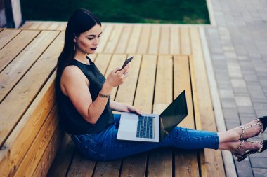 Muhteşem dalgın kadın blogger haber paylaşımı ve fikirler kişisel web sitesi içinde takipçileri ile smartphone üzerinde tartışırken trendy kıyafeti giymiş. Genç esmer bildirim telefonu dışında kontrol