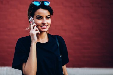 Şirin mutlu kadın kişi alan reklam ile renkli duvar yanındaki yaz yürüyüş sırasında modern telefonla konuşuyor. Pozitif blogger rekreasyon promosyon arka plan yakın kentsel ayarı, zevk