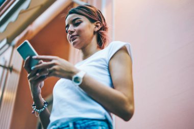 Aşağıda kadın Blogger görünümü online sosyal ağlar üzerinde modern smartphone aygıt içinde kentsel ortamda ayakta sohbet. Hippi kız casual giyim telefon açık havada üzerinde sms mesaj gönderme giyinmiş