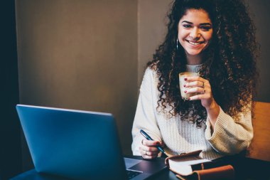 Yarım uzunluk portre gülümseyen kadın freelancer kafede kokteyl ile çalışma break zevk. Neşeli grafik tasarımcı kameraya bardak içecek tutarken bakarak Resim kırpılmış