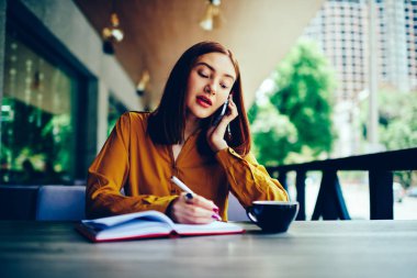 Durulması işkadını bilgileri kaydederken telefon hücresel ağ yoluyla ortakları ile konuşmayı sarı bluz giymiş. Not Defteri'ne yazmak ve telefonda konuşurken yetenekli kız öğrenci