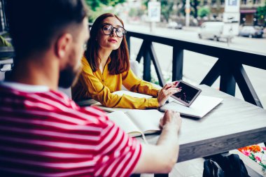 Erkek kadın meslektaşım açık havada oturma sırasında yararlı bilgiler Web sitelerinde arama için dijital tablet kullanırken kameraya bakarak gözlük ile işbirliği arkadan görünüm Resim kırpılmış