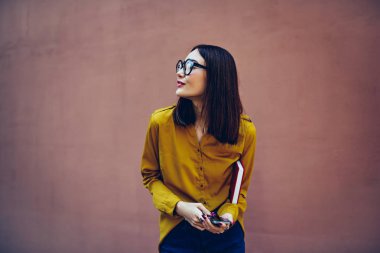 Promosyon arka plan yakın kamera için poz süre uzağa arıyorsunuz serin gözlük dalgın güzel kız öğrenci. Sevimli genç kadın için reklam kopya alanı ile duvar için karşı ayakta