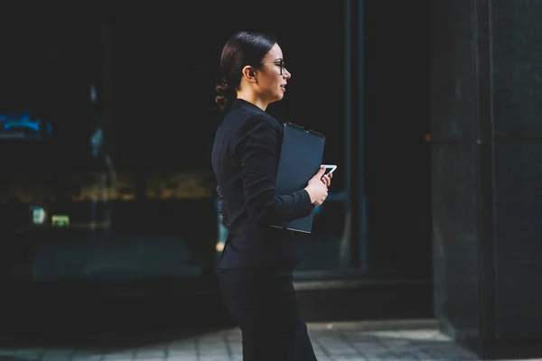 フォルダーを手で押し オフィスビル屋外広告メッセージのブレーク Time Promotional 背景に沿って散歩のスタイリッシュな黒のオフィス スーツに身を包んだ女性弁護士の側面図 — ストック写真