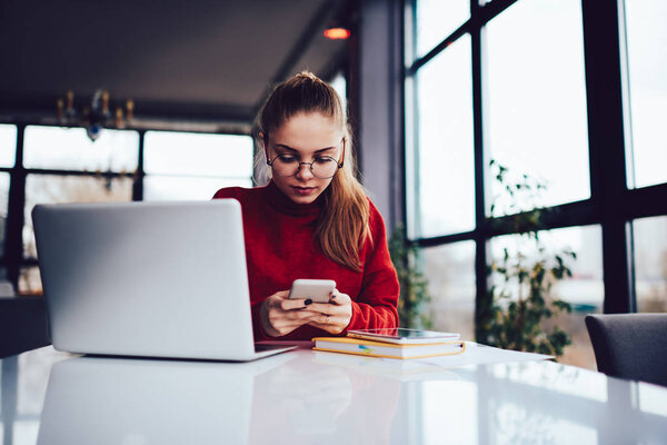 Young smiling creative female designer using modern technology during remote work indoors.