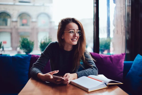 Positiv Ung Kvinna Eleganta Glasögon Tittar Bort Samtidigt Sitter Vid — Stockfoto