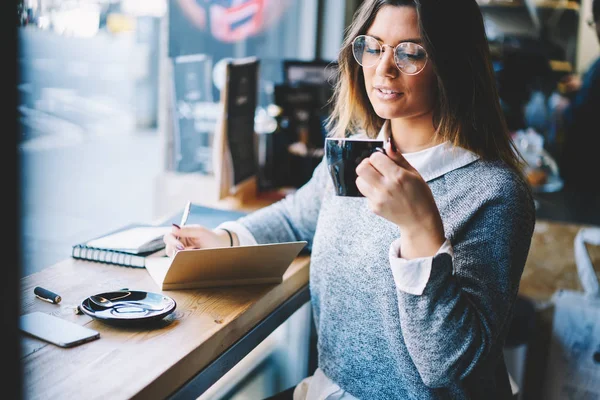 Successful Female Owner Optical Eyeglasses Enjoying Cappuccino While Noting Plans — Stock Photo, Image