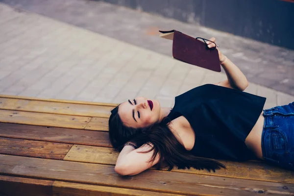 迷人的思考有才华的学生阅读信息从记事本 而躺在木凳上的城市设置 在街头的自由时间的教科书上沉思有吸引力的黑发检查时间表 — 图库照片