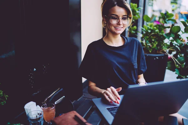 Wesoły Student Optyczny Okulary Oglądania Webinar Laptopa Siedząc Kawiarni Świeżym — Zdjęcie stockowe