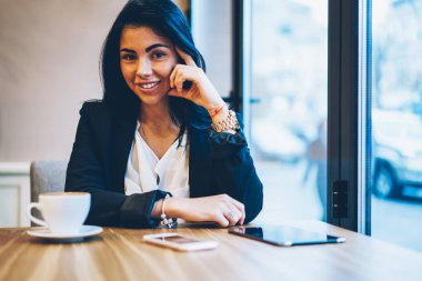 Kırpılmış görüntü gülümseyen güzel kadın kişinin kafeterya boş zamanlarında harcama yaparken kameraya bakıyor. Genç başarılı işkadını kapalı tahta masada oturan dinlenme portresi yarım uzunluk