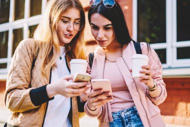 Çok kadın turist uygulama holding kahve yürüyüş akıllı telefonlar cep dosyaları eşitleme hipster kızlar Kupası için marka, tanıtım alanı ile gitmek gezinmek için güncelleştirme yükleme