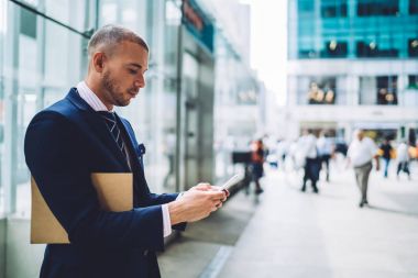 Kendine güvenen erkek avukat iş bölgesinde şehrin üstünde hareket eden telefon, e-posta açık havada colleagu için geri göndermeye smartphone cep telefonu ile kontrol ciddi erkek girişimci numarası arama açık havada duran
