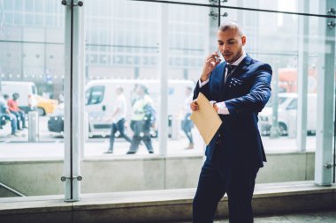 Meslektaşım, yakışıklı meşgul icra müdürü telefon görüşme sırasında Toplantı düzenleme belgeleri ile yürüme ile telefonda konuşurken ofiste zaman acele kontrol şık elbiseli ciddi iş adamı