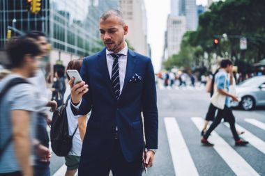 Düşünceli erkek sahibi smartphone Web sitelerinde bilgi okuma Haberler kalabalık stree üzerinde duran cep üzerinden mesaj gönderme emin Yöneticisi tarafından geçen yayalar ise konsantre