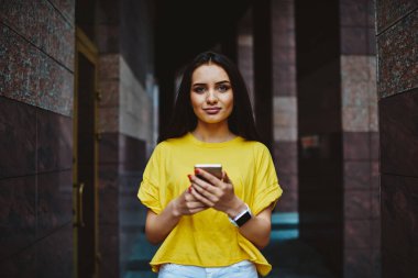 Yarım uzunluk portre rekreasyon zaman ve mesaj atıp geri bildirim sırasında kentsel ayarında cep üzerinde yürüyen güzel esmer kadın. Şirin hippi kız dışında gezinme sırasında web sayfasında online rezervasyon