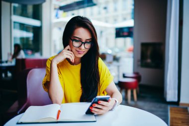 Serin gözlük smartphone için 4 g bağlı internet sitesinde ilginç video izlemek büyüleyici kadın durulması. Dalgın çekici hippi kız popüler Web sayfalarını kafede oturan haber okuma