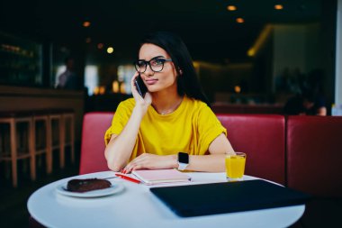 Mobil telefonla kafede otururken konuşmayı serin gözlük çekici kız öğrenci. Şirin esmer kadın kafeteryada sonu çalışma sırasında Smartphone'da söz