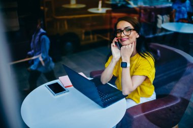 Mobil uygulama kapalı yoluyla arkadaşlarınızla iletişim sırasında kameraya bakarak mutlu genç hippi kız portresi. Kafede dizüstü bilgisayarda uzak iş sırasında molası pozitif kadın serbest meslek