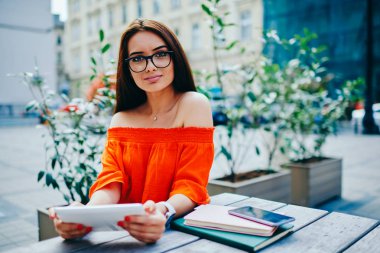 Yarım uzunluk portre sevimli esmer kameraya manifatura geribildirim Web sayfası sırasında dijital tablete bakarak bağlı 4 g için Internet. Genç hippi kız açık havada oturma becerikli alet ile yeniden