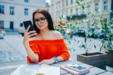 Web sayfasında smartphone içinde ilginç video izlerken gözlük genç durulması erkek için kablosuz internet açık havada bağlı. Çekici hippi kız Street serbest zaman sırasında e-posta kontrol