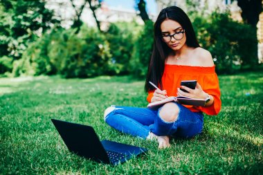 Şık kıyafet smartphone cep telefonu ile internet ve kayıt bilgileri Notepad bağlı Web sitelerine araştırma ile yaklaşan sınav hazırlama dalgın güzel kız öğrenci giymiş