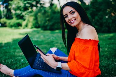 Neşeli kız öğrencinin harcama boş zaman ob portresi kırmak üniversite zevk bahar hava, kampüs içinde başarılı metin yazarı payı multimedya dosyalarını eşitleme cep telefonu ve dizüstü bilgisayar