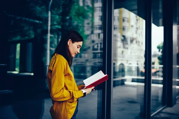 Young Clever Pondering Female Student Checking Information Red Notepad While — Stock Photo, Image