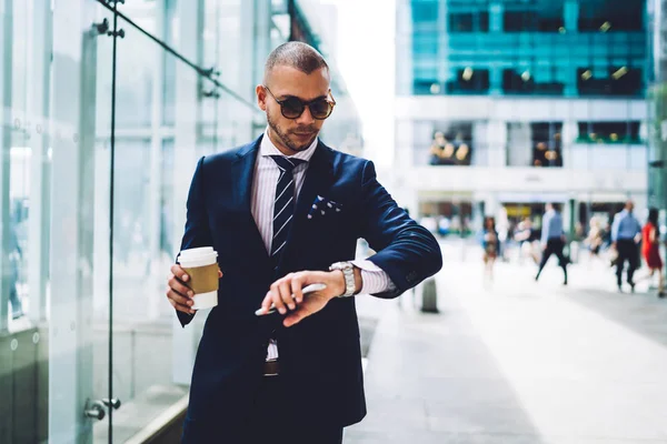 自信を持って男性起業家の Wristwatc 見てコーヒーをテイクアウトと都市の設定でフォーマルなスーツで 深刻なビジネスマンのため急いで中の休憩中に腕時計で時間をチェック — ストック写真
