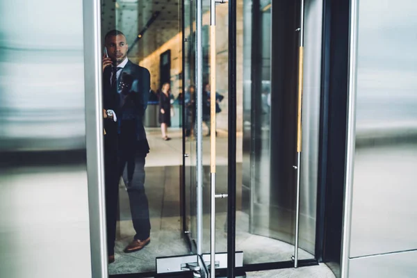 严肃的执行经理离开办公楼谈论移动关于企业 男性企业家在优雅正式西装有电话谈话 当外出从现代建材 — 图库照片