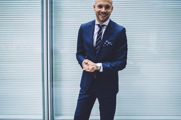 Half-length portrait of good-looking executive manager posing on promotional background prosperous entrepreneur in elegant suit satisfied with success in business standing near publicity are