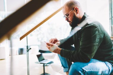 Dalgın hipster adam Eyewear evde, sipariş online harcama zaman yapma web sitesinde mağaza genç adam sosyal ağlarda telefon evinde merdivenlerde oturan kullanarak arkadaşlarınızla sohbet öğeleri seçme