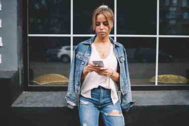Şık hippi kız üzerinde modern cep alınan sms mesajý okuma trendy kot giyim giymiş. İnternet Web sayfası tarama ve dijital Smartphone'da boş zamanlarında alışveriş yaparken genç kadın