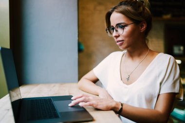 Internet Web tarama ve kafede otururken dizüstü bilgisayarda online alışveriş yaparken şık gözlük içinde çekici metin yazarı. Büyüleyici kadın grafik tasarımcı netbook 4 g ile çalışma