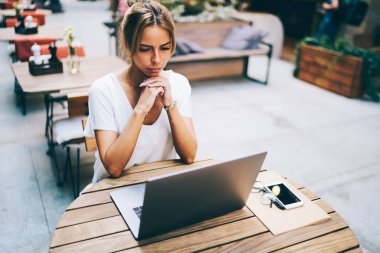 Yüksek kablosuz cihaz dijital dizüstü bağlantı üzerinde yararlı webinar izlerken konsantre genç işkadını hızda internet. Kahve Dükkanı iç bilgisayar öğrenim dalgın genç kadın