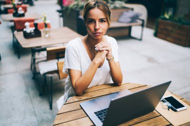 Yarım uzunluk portre çekici metin yazarı kablosuz yüksek hızlı internet bağlantısı ile kamera çalışma serbest, modern bilgisayar süre bakarak. Laptop oturan kafe büyüleyici kadın sahibi