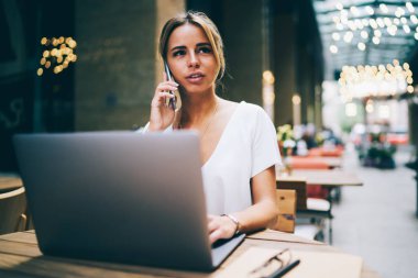 Çekici tasarımcı akıllı netbook yeni grafik proje üzerinde çalışma serbest iken iletişim. Büyüleyici işkadını dizüstü bilgisayar başında oturan ve Internet üzerinden telefonla konuşuyor