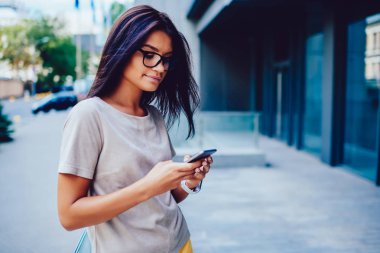 Açık havada, meslektaşı ile genç işkadını arama numarasına taksi duran modern ofis binası yakınında toplantı için beklerken ağlardan haber okuma gözlük düşünceli esmer kadın