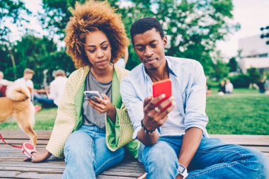 Afro Amerikalı adam durulması sosyal ağ için 4 g bağlı telefon üzerinden mesaj ilginç kadın için gösterilen modaya uygun kıyafet giymiş. Zevk açık havada dinlenme modern cihazlar ile genç Çift
